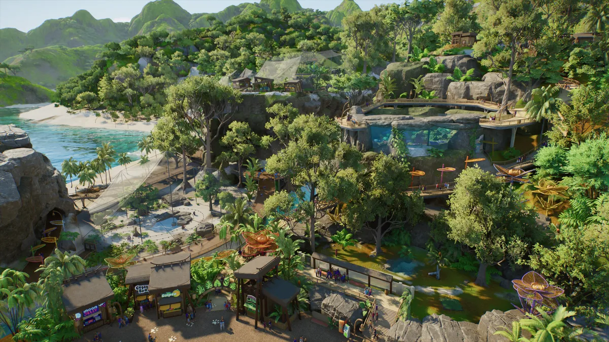 Tropical coastal zoo in Planet Zoo 2 with a cliff aquarium glass wall, wooden boardwalk and beach